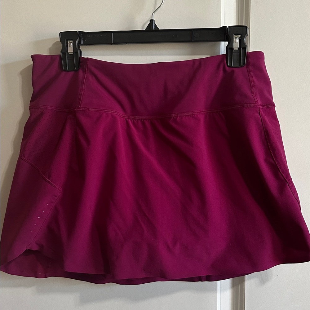 Athleta Run With It Skort 14”. Medium color is a plum/red/pink